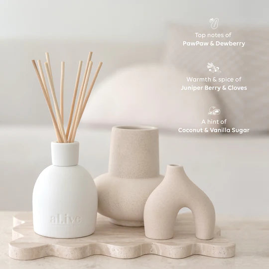 White diffuser with wooden sticks and ceramic vases on a light surface.