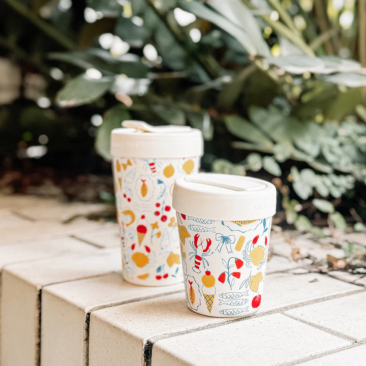 Two ceramic cups with colorful patterns on a stone surface with a blurred green background