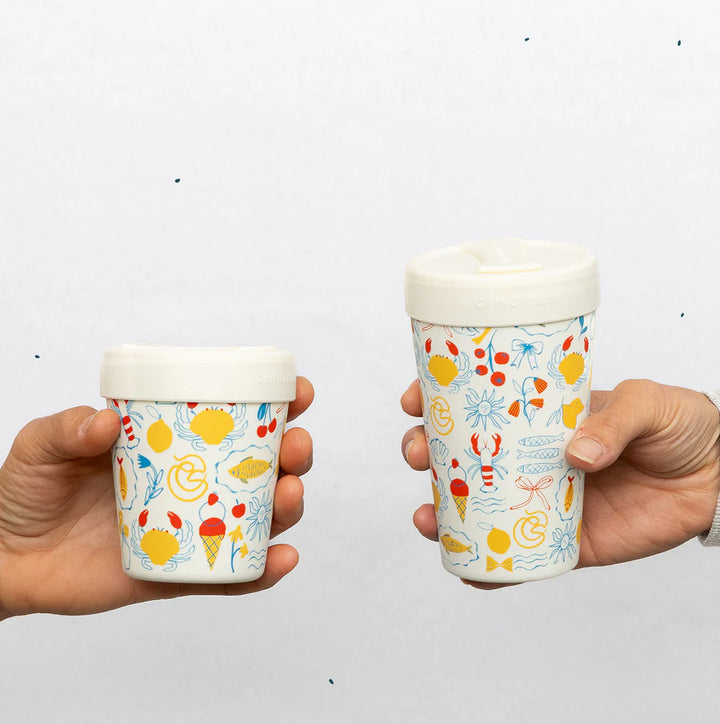 Two hands holding ice cream containers with colorful designs on a white background