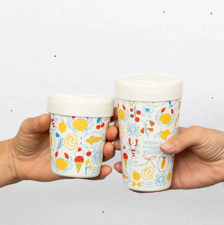 Two hands holding colorful coffee cups with a white background