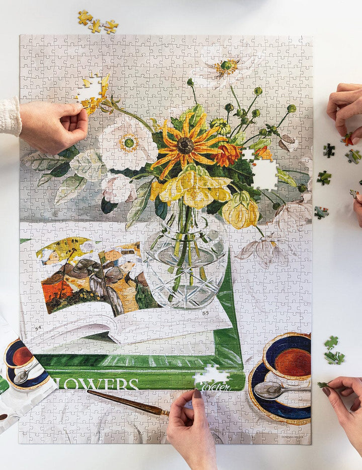 Floral puzzle with hands assembling pieces on a white surface