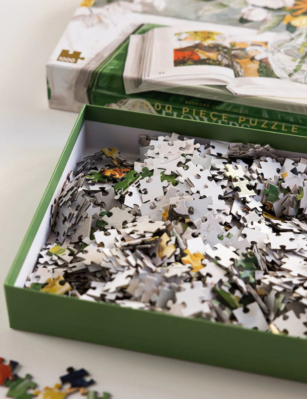 Jigsaw puzzle pieces in a box with a partially completed puzzle on top