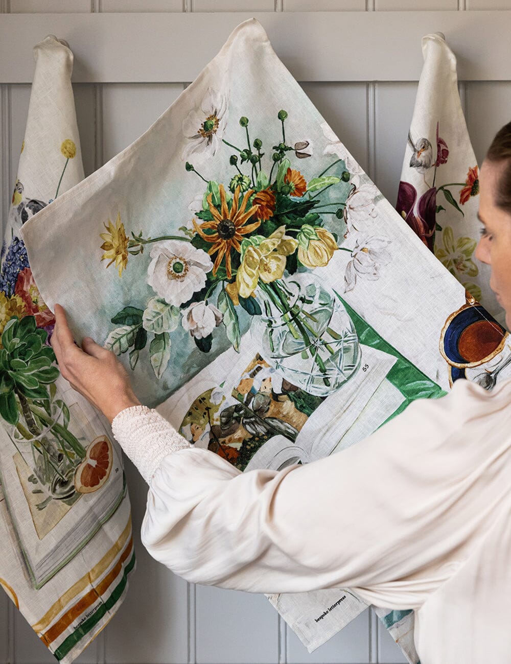 Person holding a floral-themed decorative towel against a neutral background