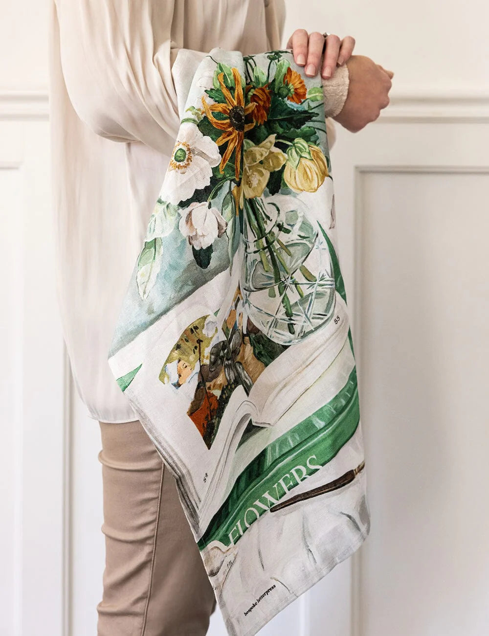 Person holding a floral-themed tea towel with a white background
