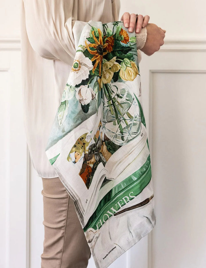 Person holding a floral-themed tea towel with a white background