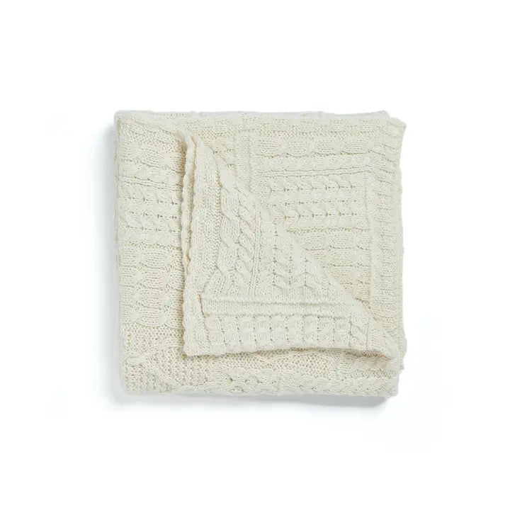 Folded cream-colored knitted blanket on a white background