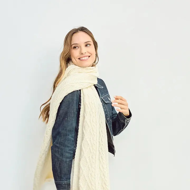 Woman wearing a cream scarf and denim jacket on a white background