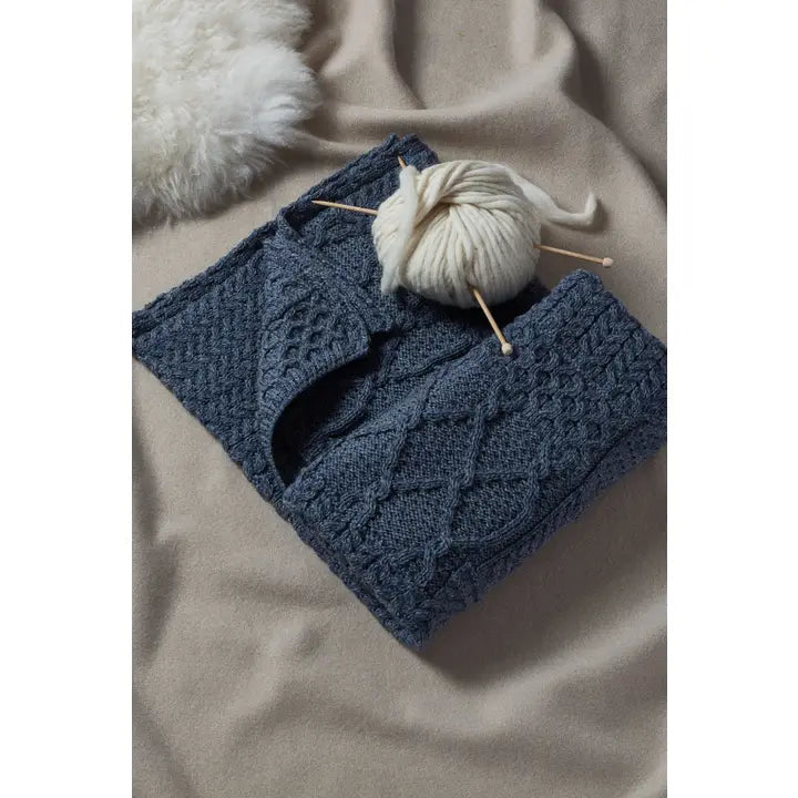 Blue knitted blanket with yarn and knitting needles on a beige surface