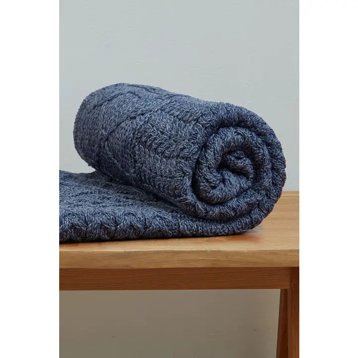 Rolled-up blue blanket on a wooden surface with a light gray background
