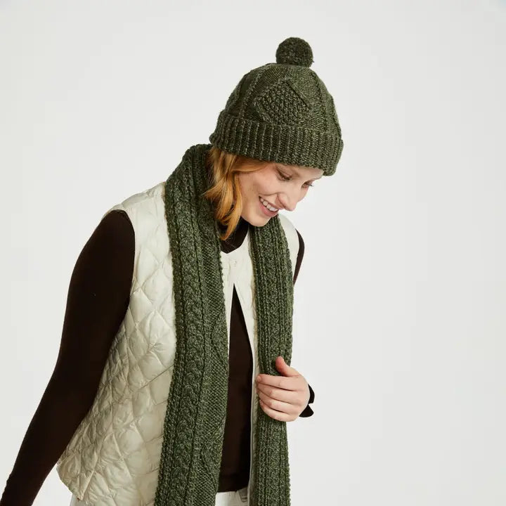 Person wearing a green knit hat and scarf on a white background