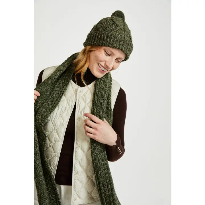 Person wearing a green knit hat and scarf on a white background