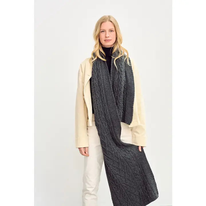 Woman wearing a long dark gray scarf with a white background