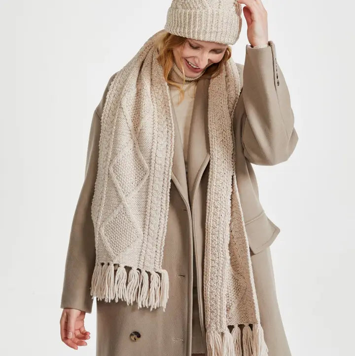 Woman wearing a beige coat, hat, and scarf on a white background