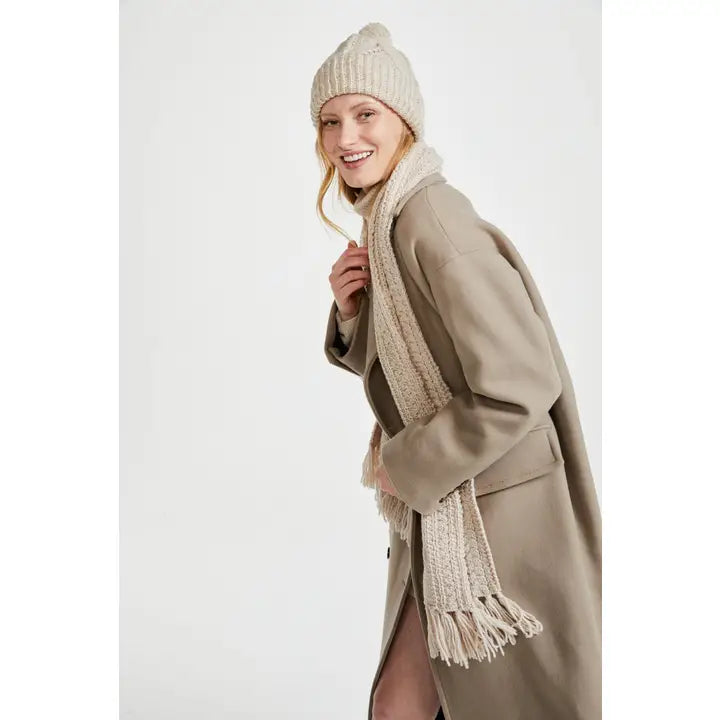 Woman wearing a beige coat, scarf, and hat on a white background