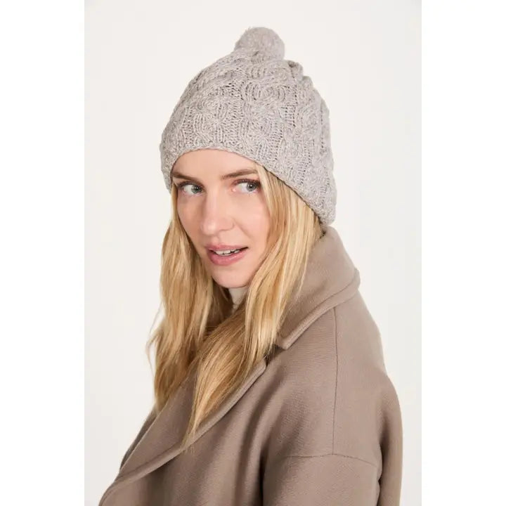 Woman wearing a gray knit beanie with a pom-pom on a white background