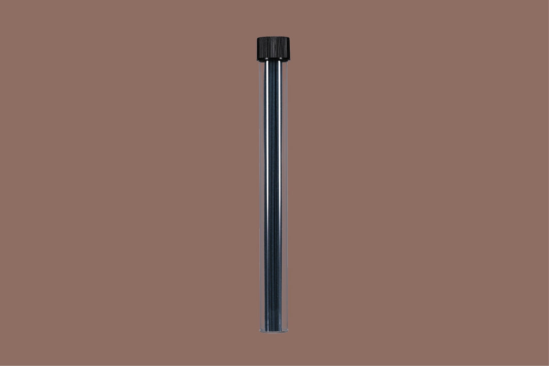 Black cylindrical object with incense sticks inside on a brown background