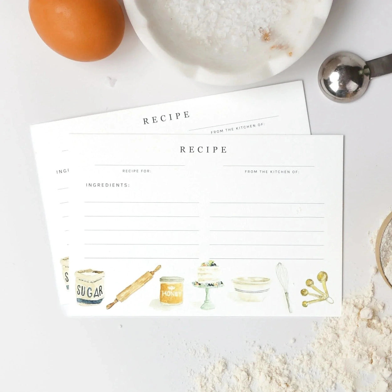 Two recipe cards on a kitchen counter with ingredients around