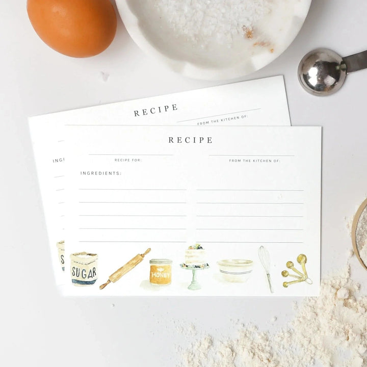 Two recipe cards on a kitchen counter with ingredients around