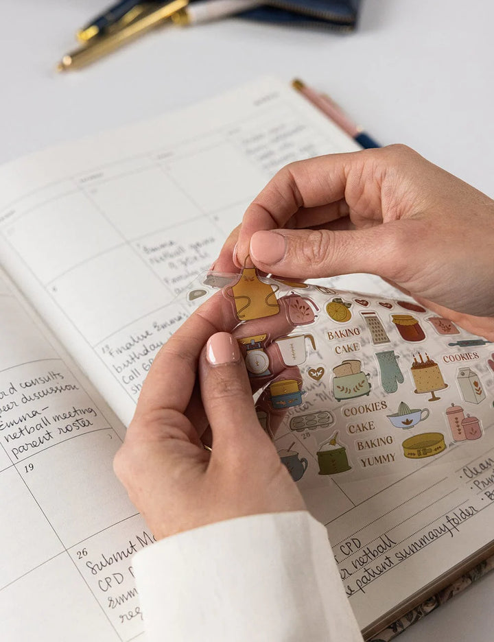 Person holding a small decorative item over an open notebook with writing.