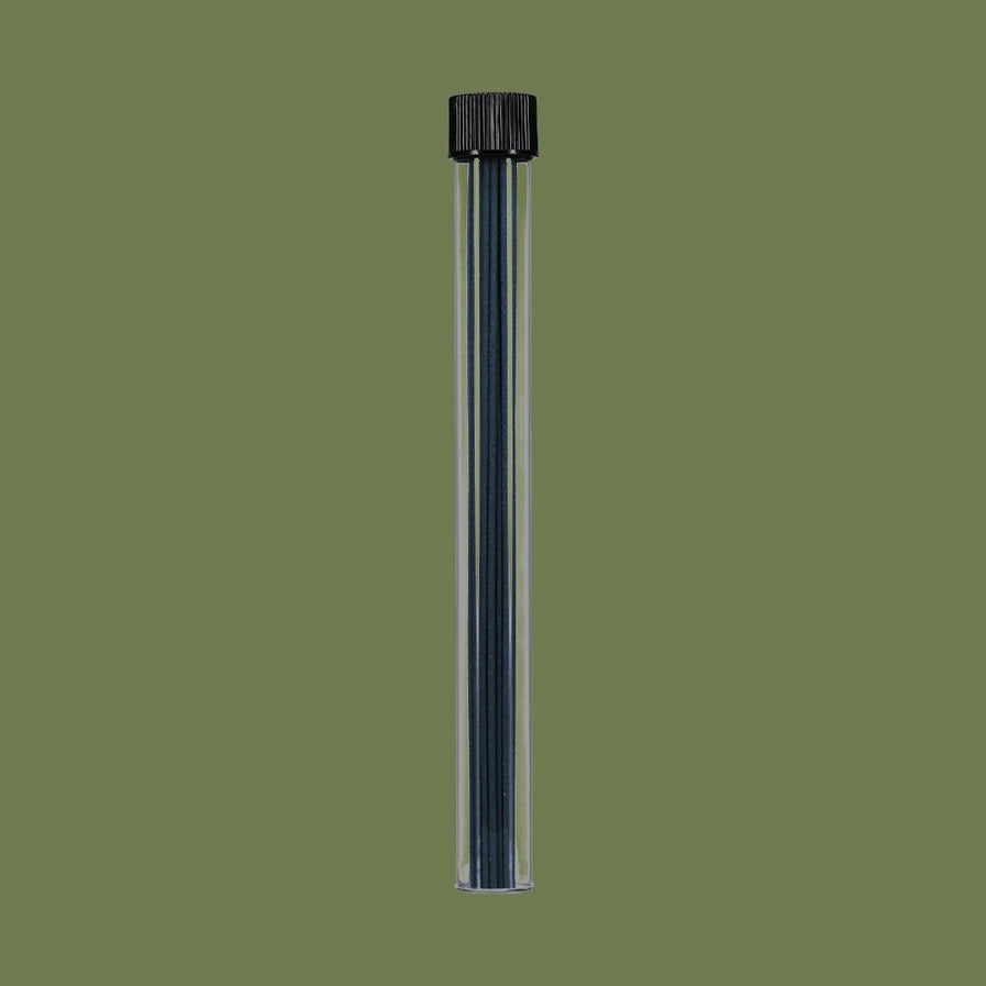 Clear plastic tube with black cap and incense sticks inside on a green background