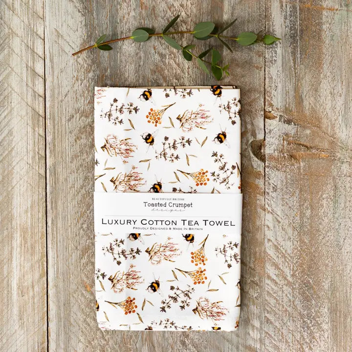Luxury cotton tea towel with floral and bee pattern on a wooden surface