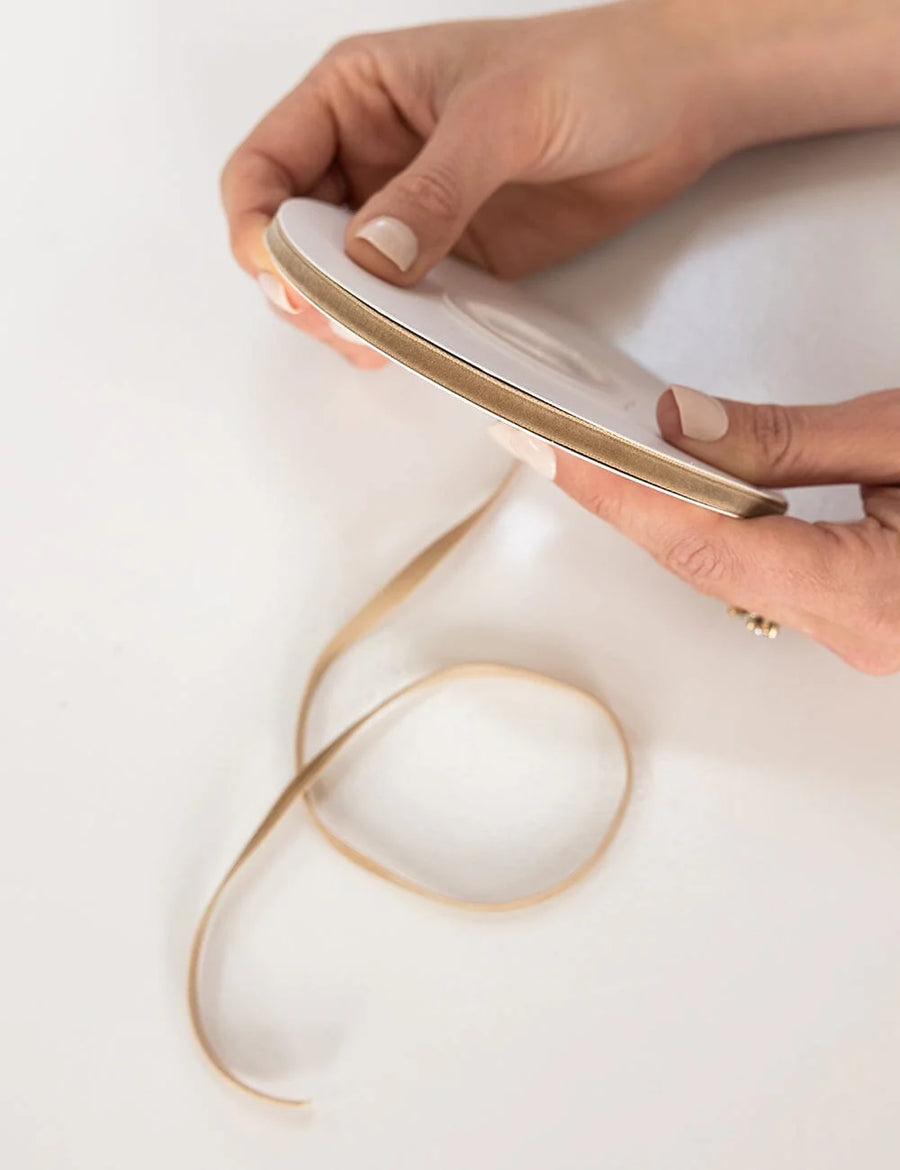 Hand holding gold ribbon on a white background
