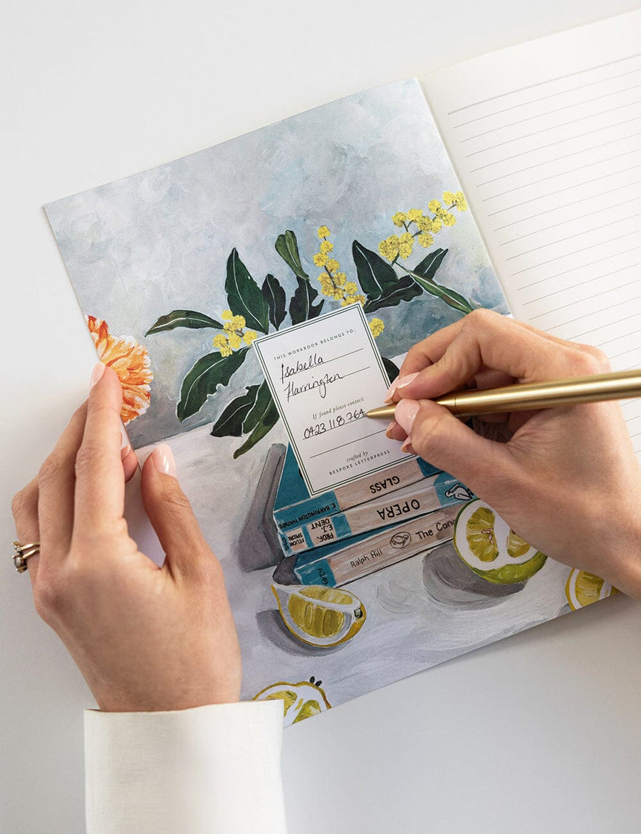 Person writing on a floral notebook with a pen