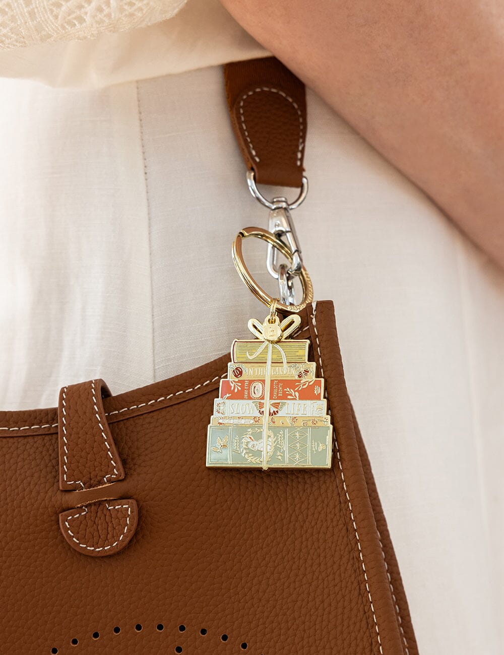 Keychain with gift box design attached to a brown leather bag.
