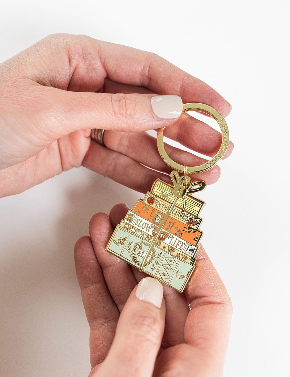 Hand holding a gold keychain with decorative design on a white background