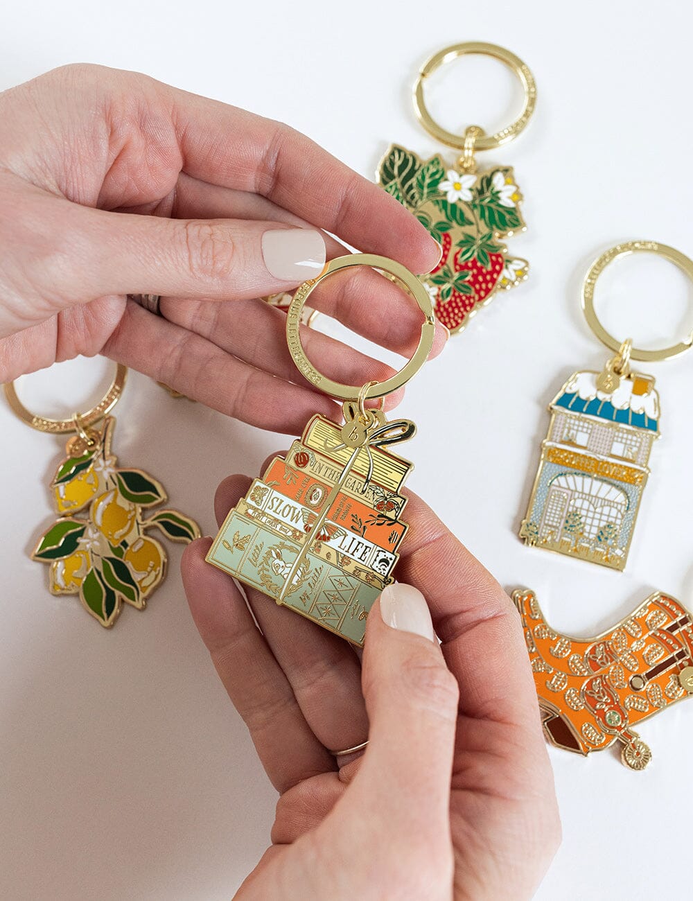 Hand holding a gold keychain with colorful designs on a white background