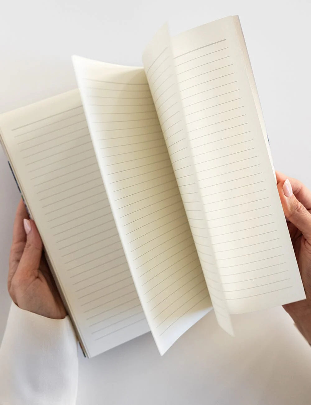 Open notebook held by hands on a light background