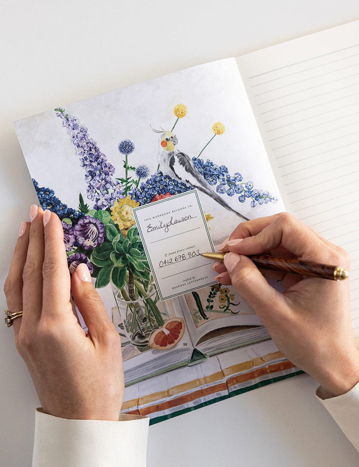 Person writing in a notebook with floral design on the cover