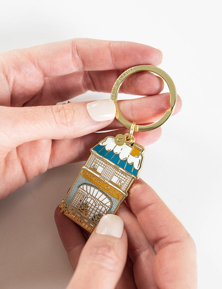 Hand holding a decorative keychain with intricate design on a light background