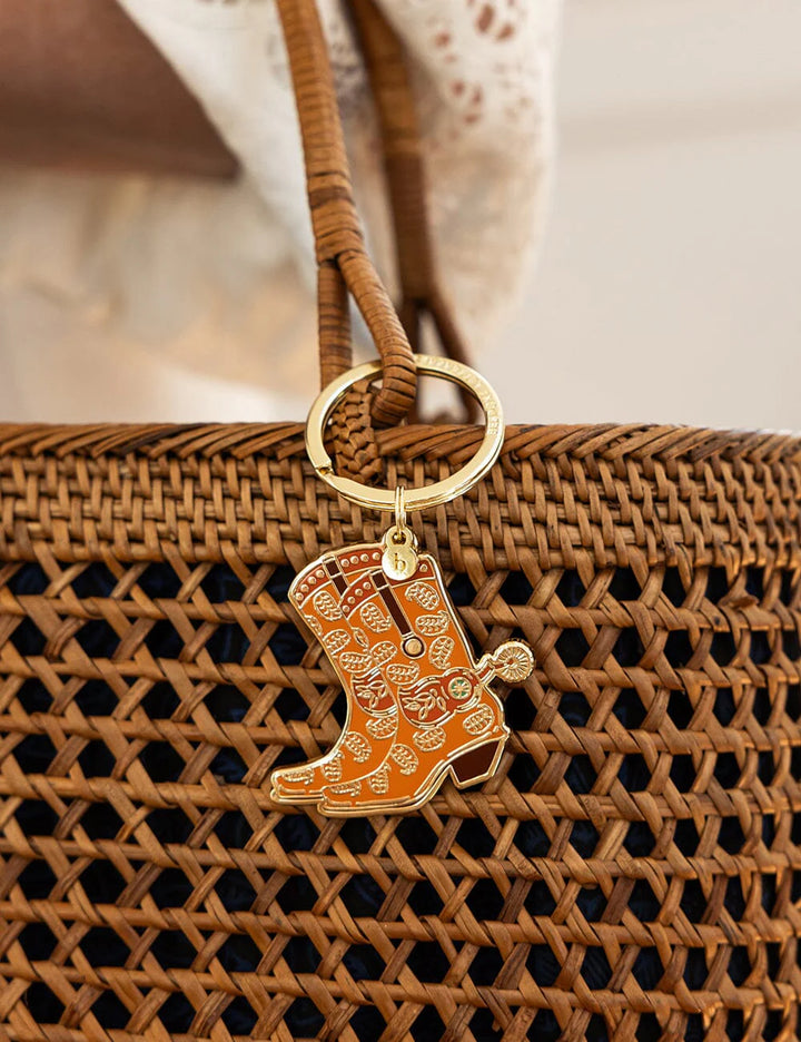 Brown woven handbag with a cowgirl boot keychain on a blurred background