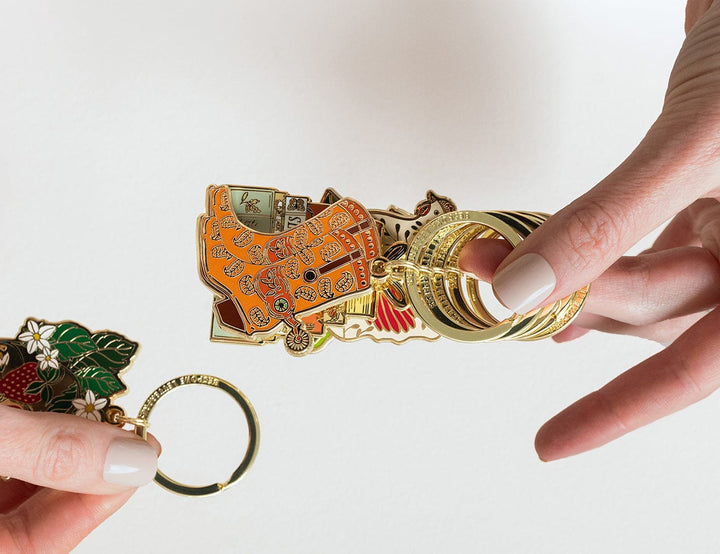 Keychain with various charms held by a hand against a white background