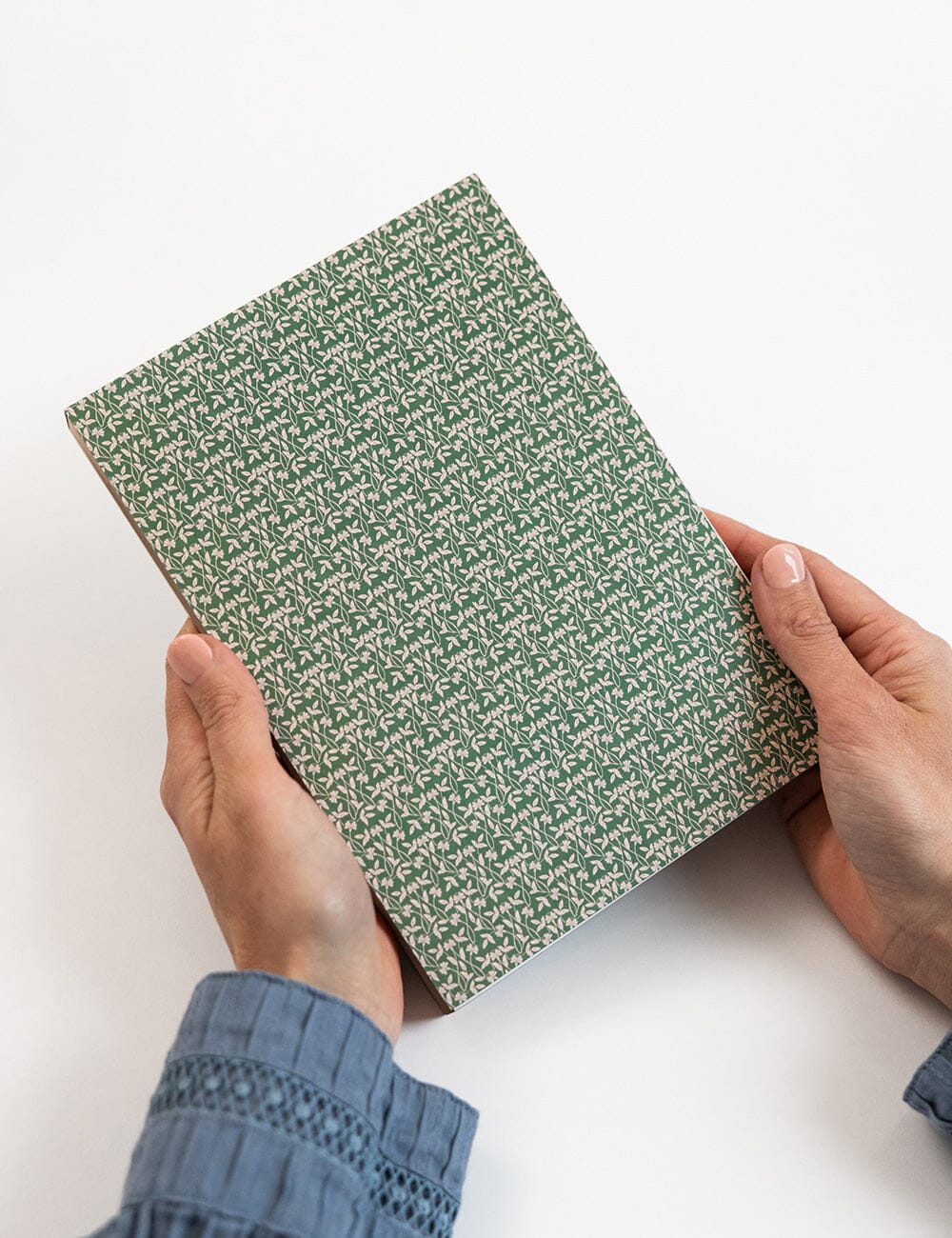 Person holding a green patterned book on a white background