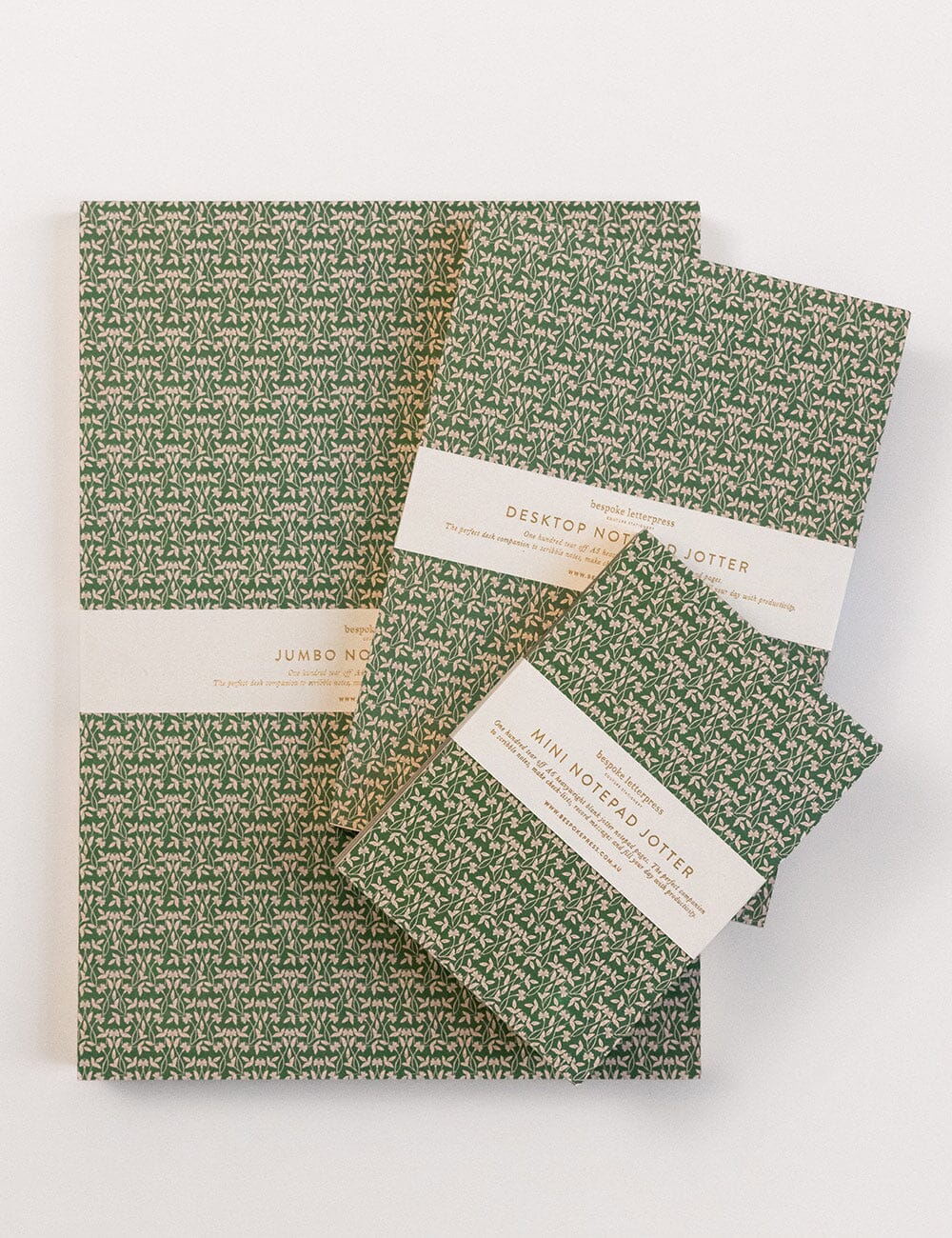 Set of green patterned notebooks with white labels on a white background