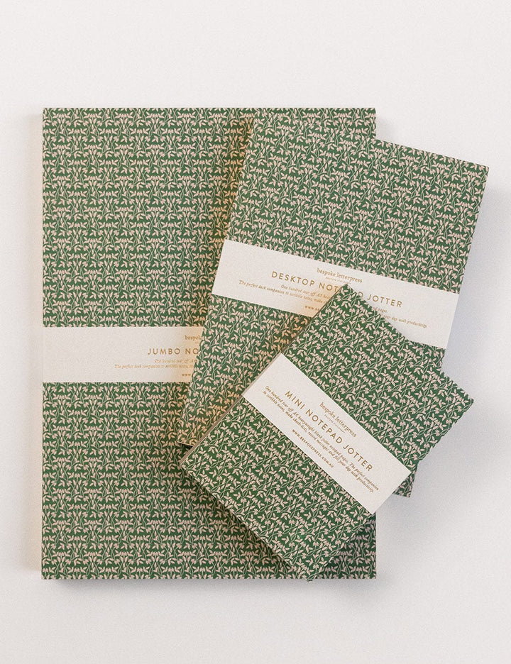 Set of green patterned notebooks with white labels on a white background