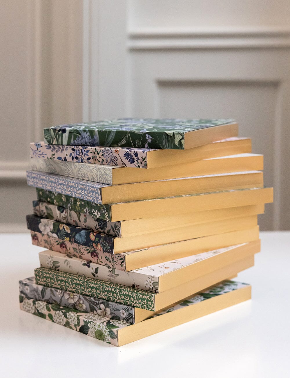 Stack of books with floral and patterned covers on a white surface