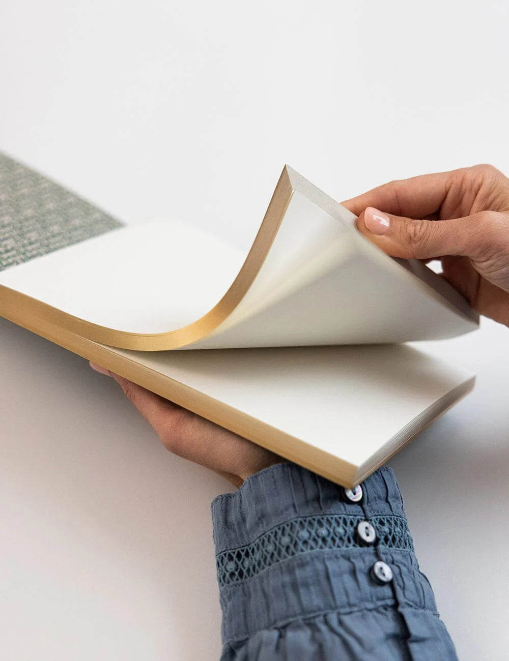 Person holding an open book with a plain background