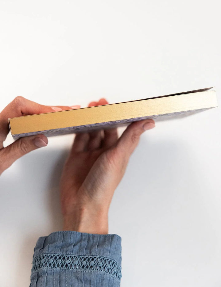 Person holding a gold-bound book on a white background
