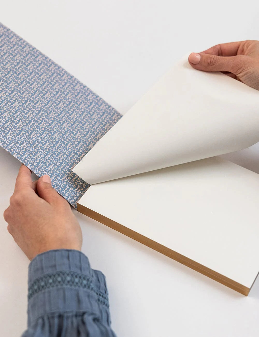Person applying blue wallpaper to a white wall