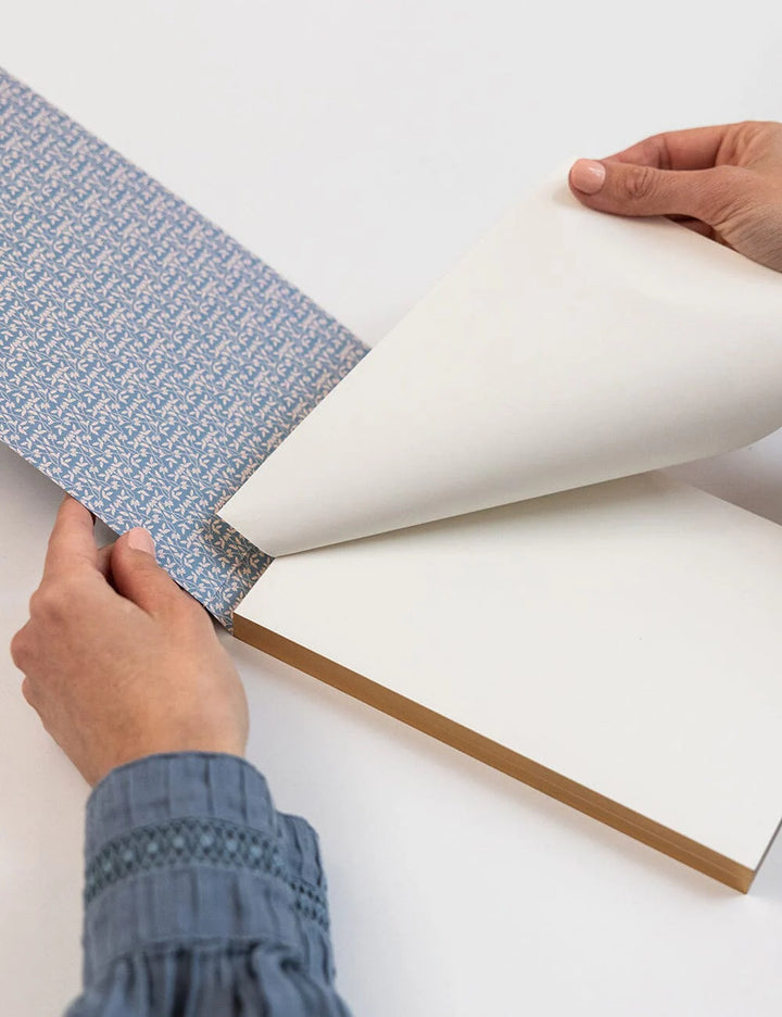 Person applying blue wallpaper to a white wall