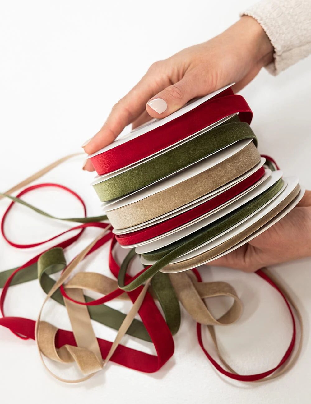 Hand holding a stack of colorful ribbons on a white background
