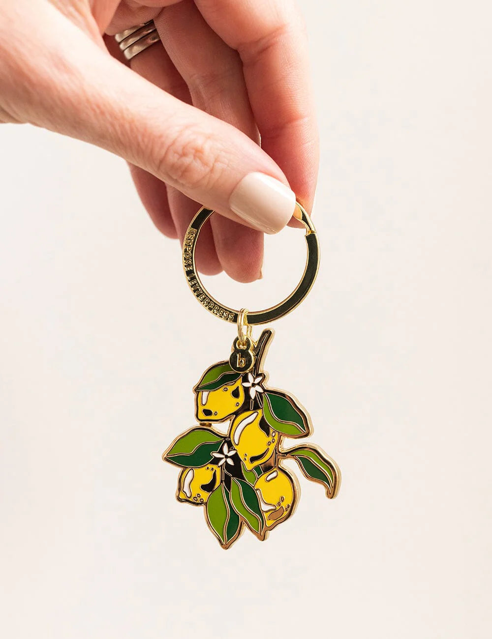 Hand holding a keychain with lemon design on a light background