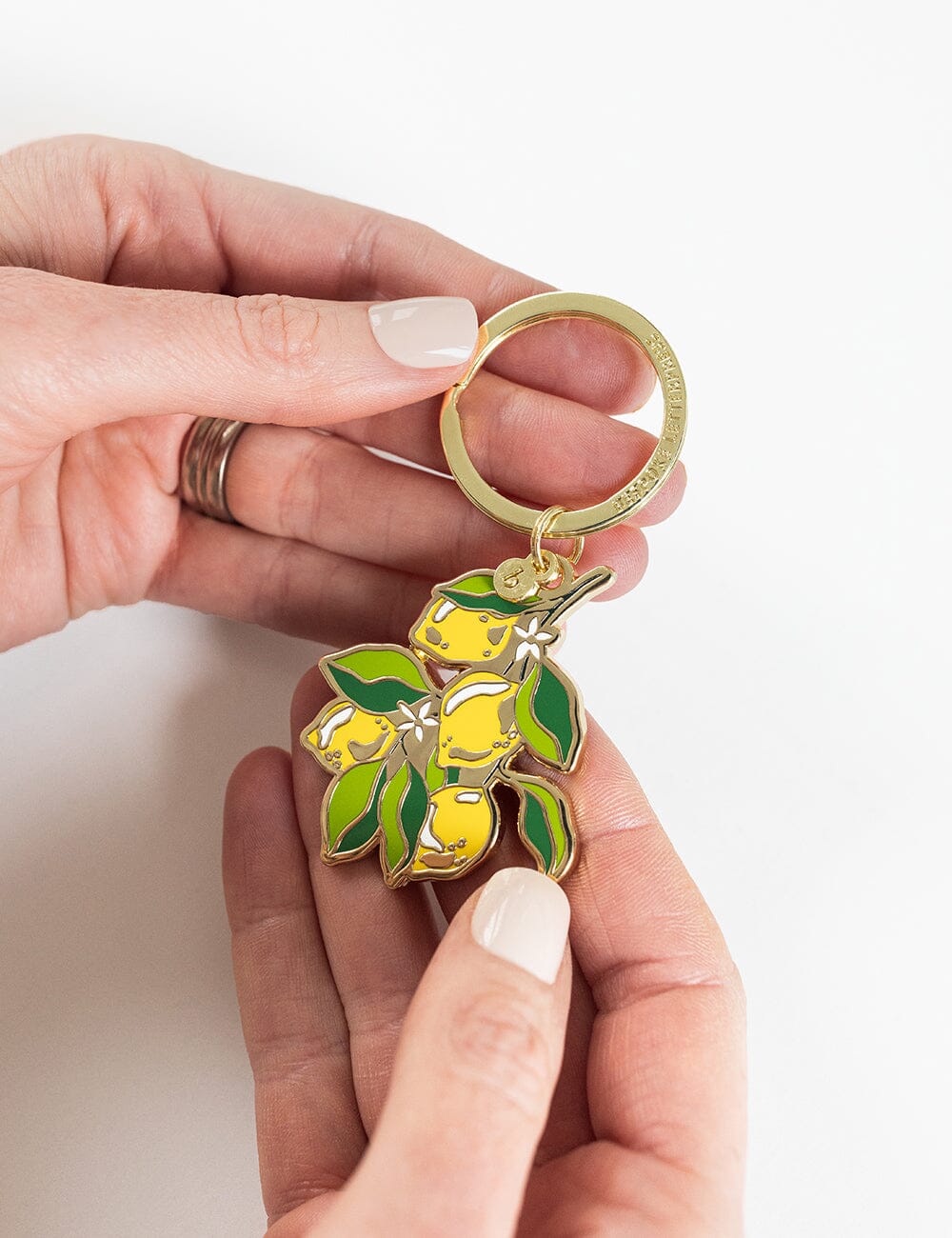 Hand holding a keychain with lemon design on a white background