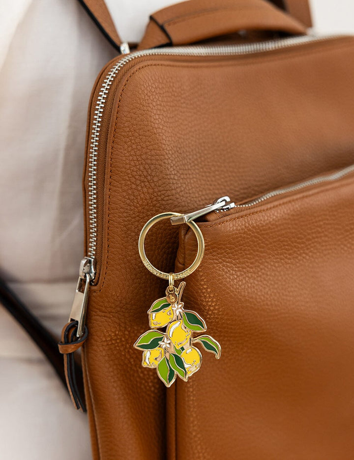 Keychain with lemon design attached to a brown leather bag