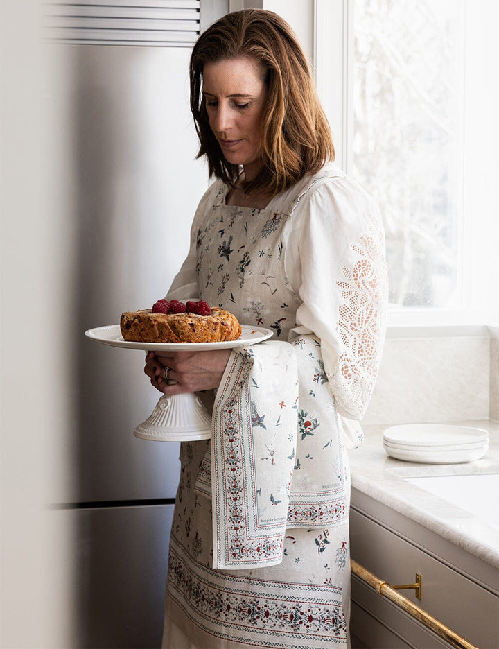 Woman holding a plate with a cake in a kitchen
