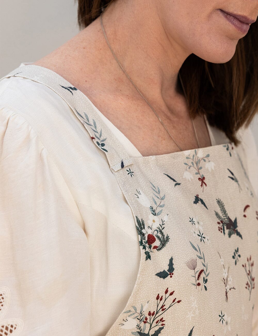 Person wearing a floral apron with a neutral background