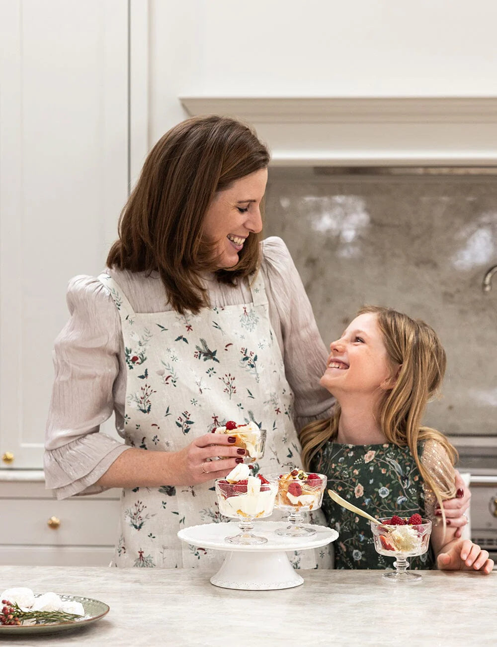 Woman and child in a kitchen with desserts on a counter